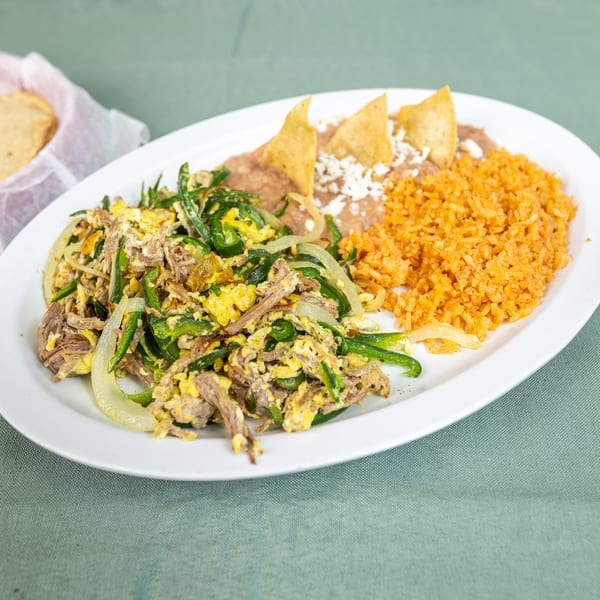 Shredded beef and egg scramble with peppers and onions, alongside rice, refried beans, chips, and tortillas.