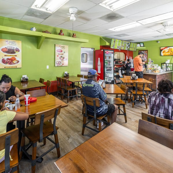 Customers enjoy meals at wooden tables inside a casual Doña Elena Pozoleria restaurant.
