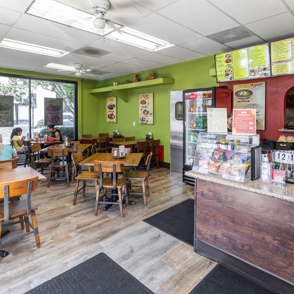 Doña Elena Pozoleria interior with diners, wooden tables, green walls, and a service counter.
